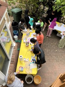 kids standing around tables tie dying t-shirts